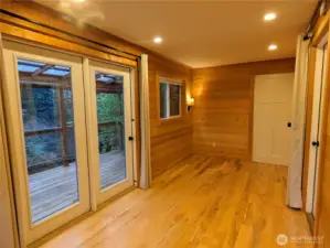 There is space for a queen size bed plus a small table and lounge chairs. The white door leads to the bathroom. There are large glass doors on both sides of the studio for a lovely summer breeze or winter snowfall viewing.