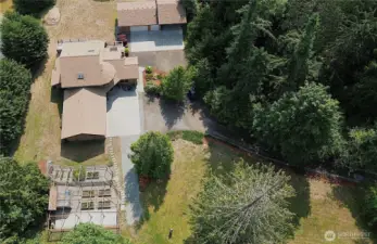 View of your raised garden, home with 3-car attached garage and detached 3-car garage with RV cover.