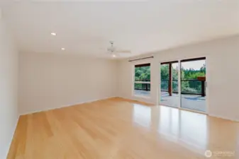 The living room, with its large windows allows this living room to be bathed in natural light. Beyond, the glass slider reveals a deck, where the garden invites you to step outside. This seamless flow creates a perfect space for relaxation and entertaining.