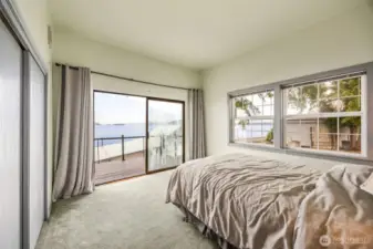 The primary bedroom features a sliding glass door that opens directly onto the deck—offering ever-changing southerly views and a seamless connection to the tranquil waterfront setting.