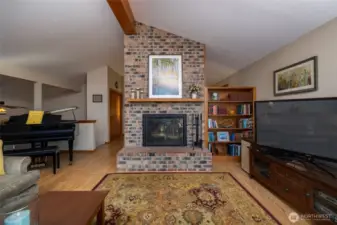 Living room with wood burning fireplace and vaulted ceilings.