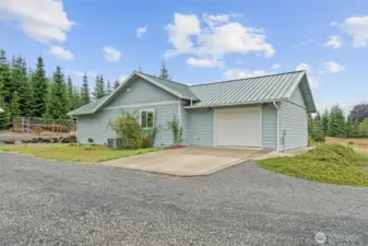 Exterior view highlighting attached garage, easy maintenance metal roof and clean design.