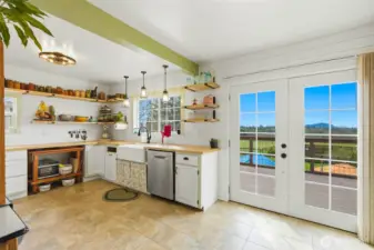 Farm style apron sink, open shelving, updated lighting and butcher block counter tops frame this country kitchen.