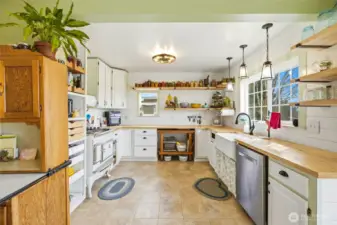 Bask in the warmth of this charming kitchen and all the wood accents from butcher block counter tops to open wood shelves.