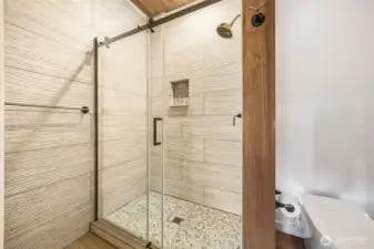 Walk in shower with tile walls.
