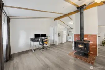 View to the left when entering the home. Functioning wood stove as second heat source.  Great room concept.