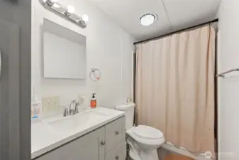 Second full bathroom; new flooring, fixtures, solid surface countertop, cabinetry; conveniently located near bedrooms two and three.