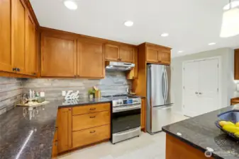 The kitchen also features stainless steel appliances, abundant storage, and a beautiful tile backsplash. The double doors in the background open to the pantry.