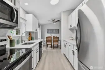 White cabinetry and stainless steel appliances define this thoughtfully designed, easy-to-navigate galley-style kitchen.