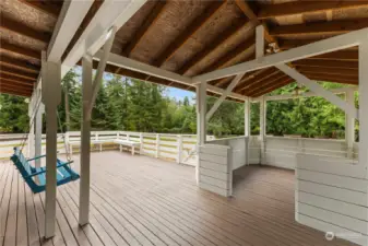 the back deck features a porch swing and additional space for a hot tub or table