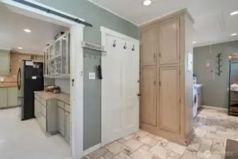Kitchen on right, barn door entry to mud/laundry room, more storage options, basement access door, laundry room, dog door access on rear entrance of home