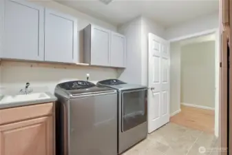 Utility room between hallway and garage. Love the storage, handy sink and included washer and dryer.