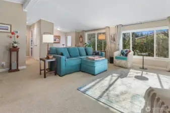 Formal living room with vaulted ceilings, sliding door to front patio and picture window overlooking the community greenbelt and trail