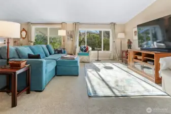 Formal living room with vaulted ceilings, sliding door to front patio and picture window overlooking the community greenbelt and trail