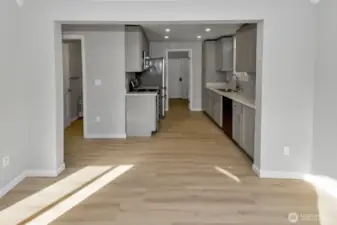 Living room looking into beautifully updated kitchen space with new cabinetry and quartz countertops