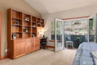 Primary suite features built-in cabinets and desk, French doors lead to private deck.