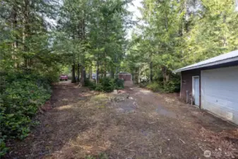 Driveway from wood framed shop along back property line to metal framed shop.