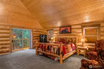 pacious primary suite with vaulted tongue-and-groove ceilings, custom log craftsmanship, and private deck access overlooking the evergreens.
