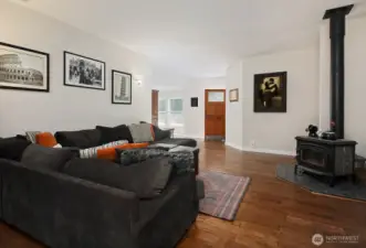 Looking back at the front door. Cozy wood stove throws off plenty of heat during the cooler months. The hallway to the 2nd Bedroom and two offices/flex rooms are around the corner from the wood stove.