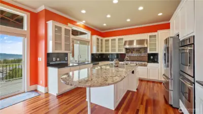 A chef's dream: spacious gourmet kitchen with an expansive island, granite countertops, top-tier GE Elite appliances, 5-burner Jenn-Air gas stove and double ovens.