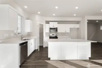 Spacious open-concept kitchen featuring shaker cabinets, quartz countertops, large center island, stainless steel appliances including gas range and built-in microwave, undermount sink, and luxury laminate plank flooring. Photos are representative only and may display different color package and/or upgrades.