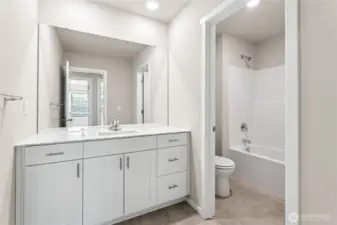 Full hall bathroom featuring single vanity with light shaker cabinets, quartz countertop, mirror, door on the water closet and tub/shower combo with white surround. Photos are representative only and may display different color package and/or upgrades.