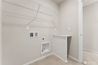 Upstairs laundry area with wire shelving, washer and dryer hookups, and utility connections conveniently located near the bedrooms. Photos are for example only. Model home of the same plan and may reflect different colors and options.