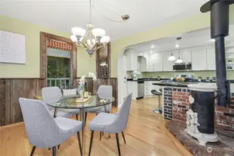 The delightful dining area has vintage wood paneling. The kitchen is complete with stainless steel appliances, a breakfast bar, white beadboard cabinetry, and granite counters. The vintage wood stove is for decorative purposes only.