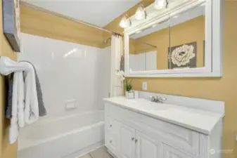 Lower level full bathroom features a cast iron tub, tile flooring and a custom vanity.