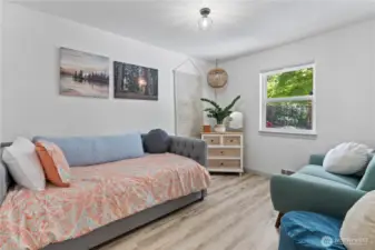 This cozy and inviting guest room is filled with natural light and soothing tones. Featuring a stylish daybed, soft hardwood-style flooring, and nature-inspired decor, it’s the perfect space for rest, reading, or a home office. A large window provides peaceful backyard views and a refreshing connection to the outdoors.