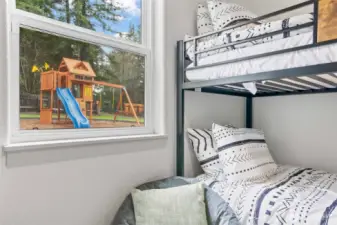 This adorable peek from the bunk room highlights the backyard playset just steps away, perfectly visible from the bedroom window. Parents can relax while keeping an eye on outdoor fun from the comfort of inside—making this home a true blend of comfort, safety, and family-focused design.