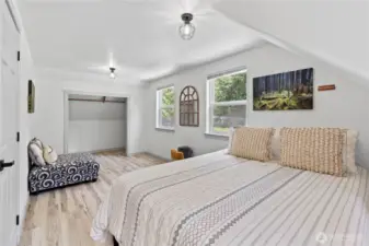 This serene upstairs bedroom features soft natural light, cozy sloped ceilings, and a spacious layout with room for both rest and relaxation. The dual windows overlook the lush backyard, while the open closet nook adds practical storage potential. Light wood flooring and neutral tones make this space feel bright and inviting.
