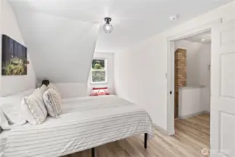 This second angle reveals a cozy window alcove ideal for a reading nook or extra seating. The room flows naturally from the hallway’s brick accent chimney and offers a peaceful, stylish retreat. Clean lines, soft textures, and great natural light define this comfortable upstairs suite.