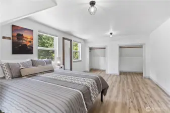 This generously sized primary bedroom features two large closets, providing ample storage and organization. The layout offers room for a seating area or additional furniture, while oversized windows bring in natural light and offer tranquil views of the surrounding greenery.
