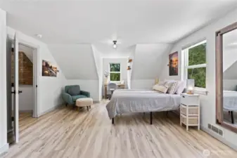 This versatile bedroom includes a built-in reading nook and workspace, perfect for remote work or study. Sloped ceilings add charm while natural light from three windows creates an uplifting atmosphere. A serene and functional space ideal for everyday living.