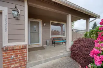 Covered front porch surrounded by lush landscaping.