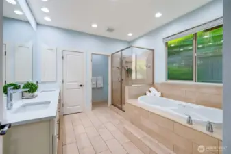 The roomy primary en suite bathroom with radiant floor heating. Double sinks and beautiful quartz countertops. Textured glass window allows the light in while maintaining privacy.  Linen closet is center with the separate toilet room to the right for added privacy.