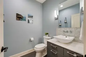 Main floor powder room with quartz countertops and glass tile backsplash.