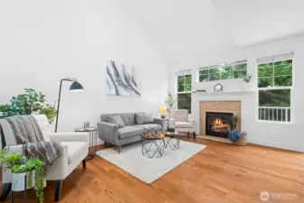 Spacious living room with vaulted ceiling, a cozy gas fireplace and mature landscaping for privacy.