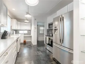 Updated kitchen featuring Corian countertops, tile flooring, and abundant cabinetry