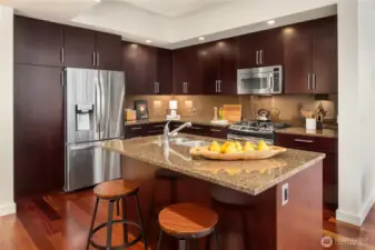 Floor to ceiling wood cabinetry with stainless appliances and gas cooking.