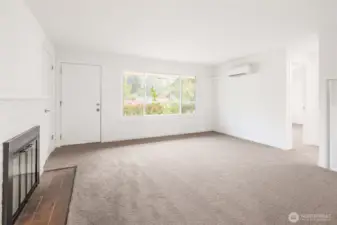 Comfortable front living space with new carpet, wood buring fireplace, and ductless mini split