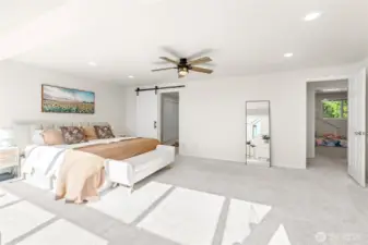 Primary bedroom with sliding barn door to en suite full bathroom and closet