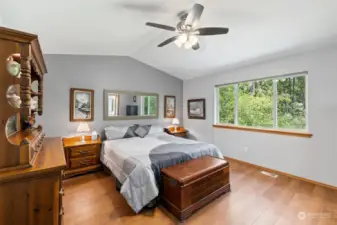 Primary bedroom with Vaulted ceiling, ceiling fan, spacious (fits bigger furniture!), and large window to enjoy your private lush view from your bed!