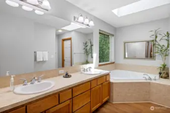 Double vanity, corner soaking tub Primary bathroom with Aqua Interlock flooring and TWO Closets, skylight, and Tiled counters and tile surround corner soaking tub!