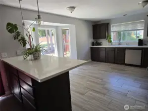 Sun-filled kitchen nook framed by bay windows offers a beautiful space for casual meals, with backyard views and ample natural light.