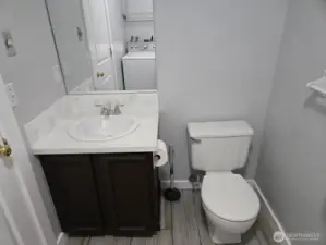 Main-level half bath with shared laundry room. Features updated flooring and stylish vanity for a modern touch.