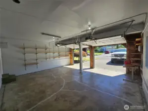 Spacious two-car garage with automatic openers and overhead lighting offers plenty of room for vehicles, tools, and hobbies. A built-in workbench and wall shelving provide ideal organization for any DIY enthusiast.