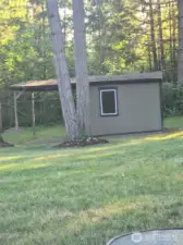 Tucked away in the serene backyard, this detached outbuilding offers ideal storage or workshop potential. Surrounded by evergreens, it’s the perfect private space for hobbies or lawn equipment.