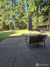Kick back in your private forest retreat. This patio setup invites cozy conversations under the canopy of Northwest evergreens, with room to expand your outdoor living space.